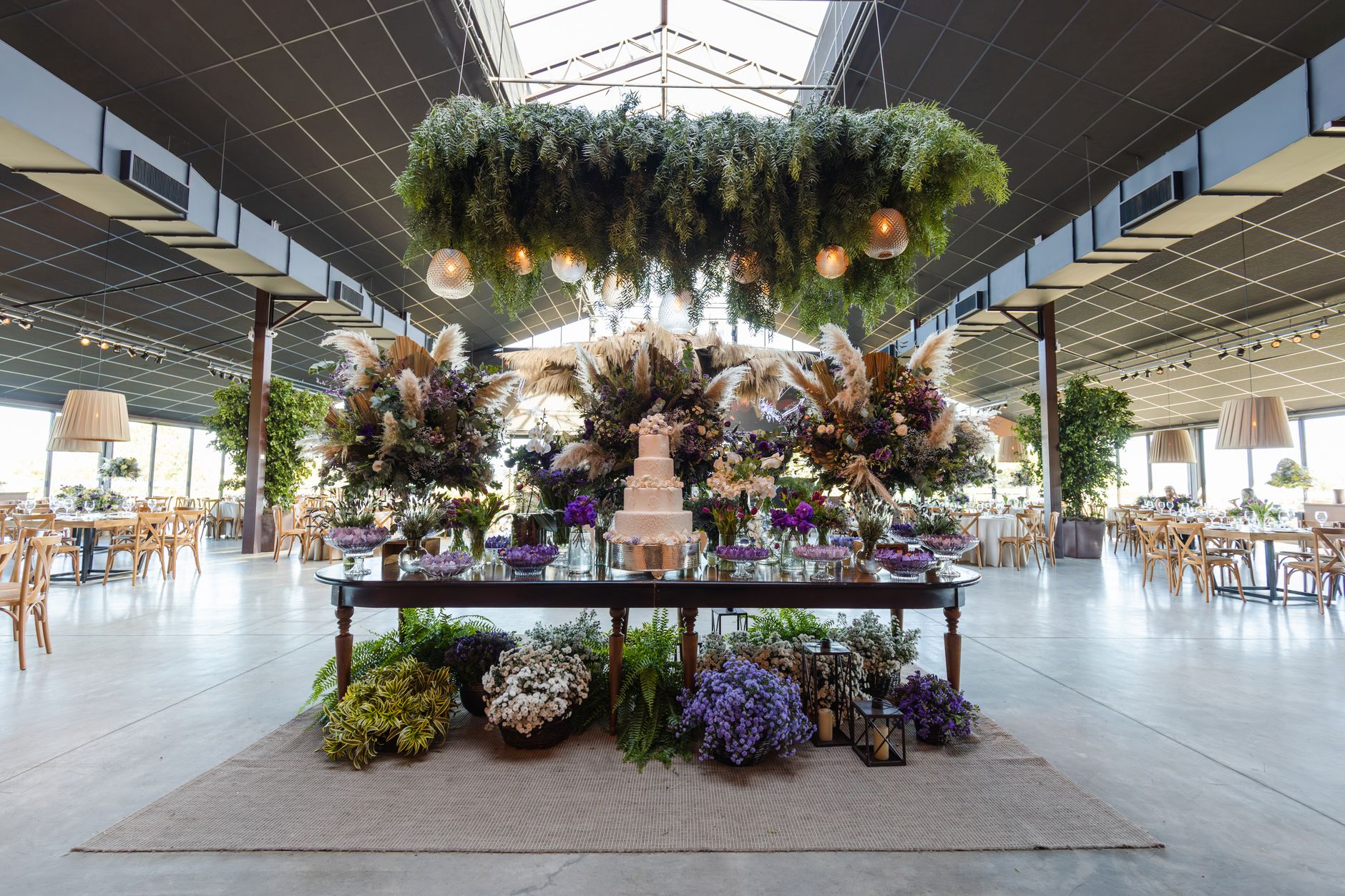 Stunning indoor wedding venue with floral arrangements and a multi-tiered cake on a decorated table. — How to Get a Vintage V